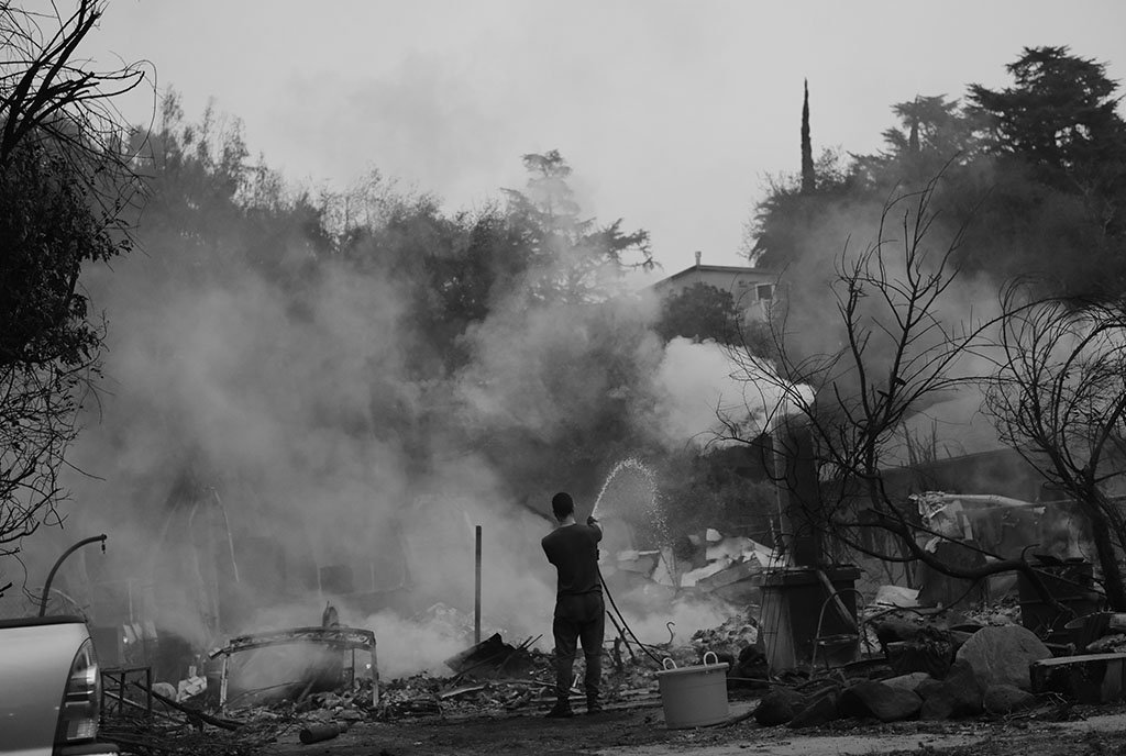 Local resident hoses Altadena fire in California. January 2025.