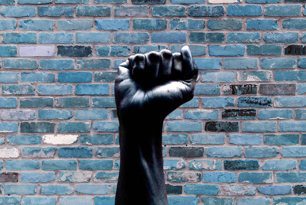 A fist of determination held up against a brick wall