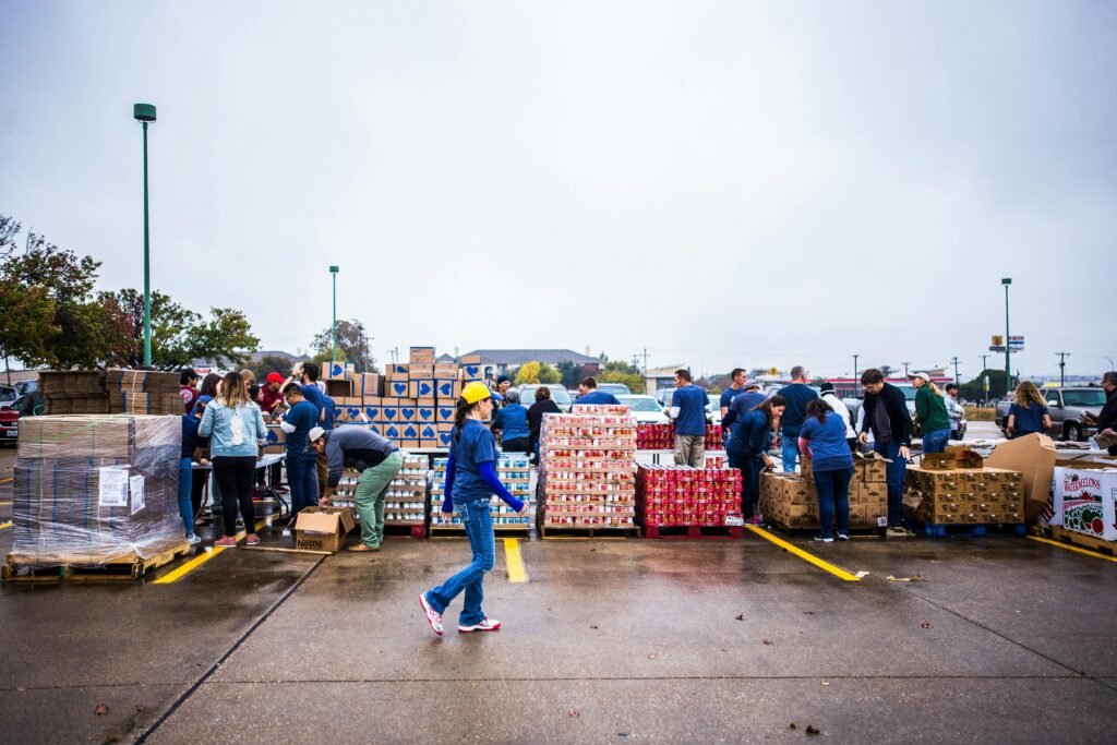 A group of people and supplies gathered in a parking lot, showing the work of volunteers to respond to a community in need.