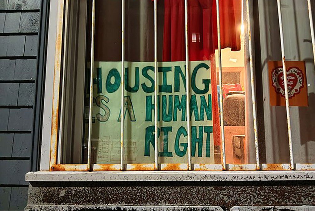 A sign posted in a tenant’s window reading, “Housing is a Human Right”.