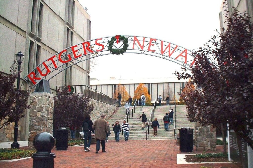 A picture of a wide outdoor public stairway that passes under a large sign that reads “Rutgers-Newark.”