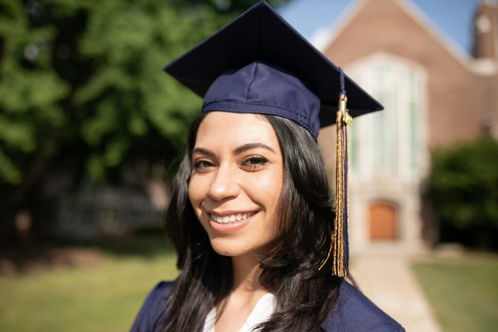 A close-up photo of a smiling woman with dark hair wearing a graduation cap.