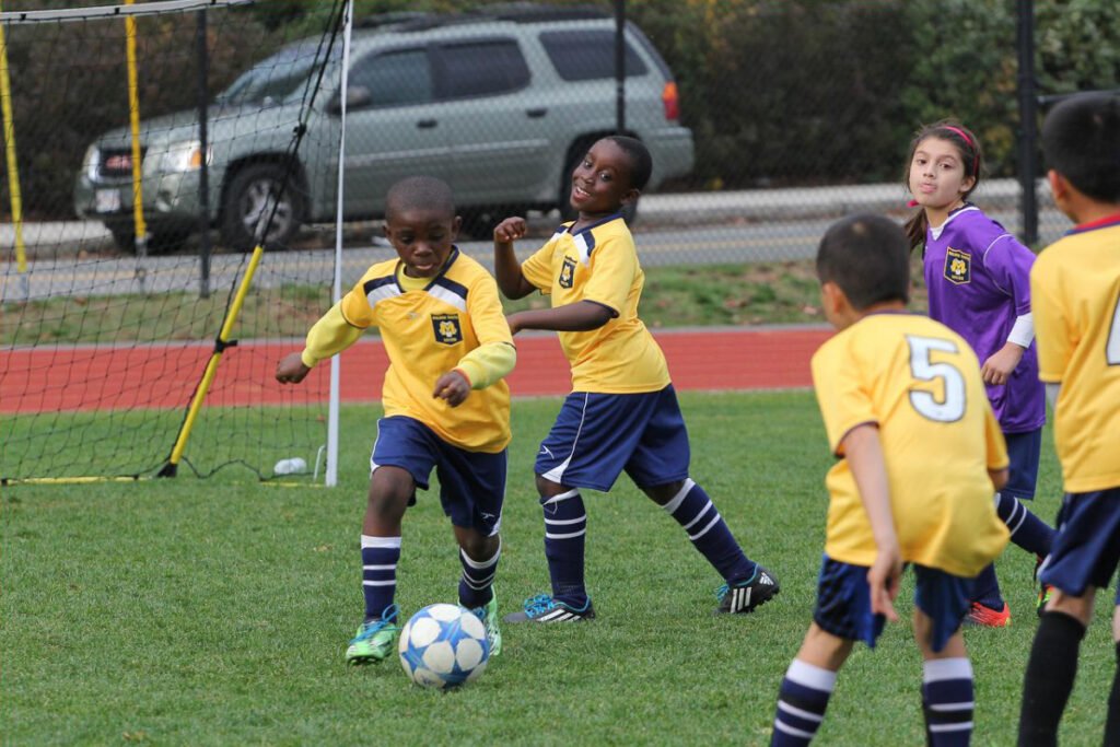 A co-ed under-10 soccer game. Pictured are four youth wearing yellow jerseys and one youth wearing a purple jersey.