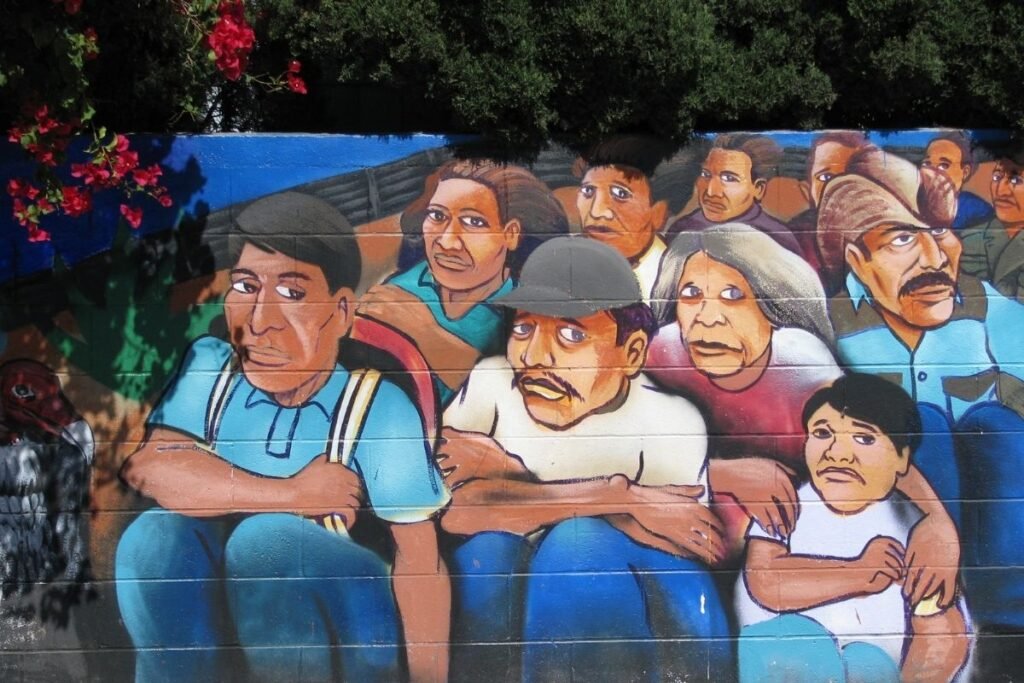 A mural shows a group of 11 immigrants, who are arranged in three rows. The people have concerned looks on their faces.