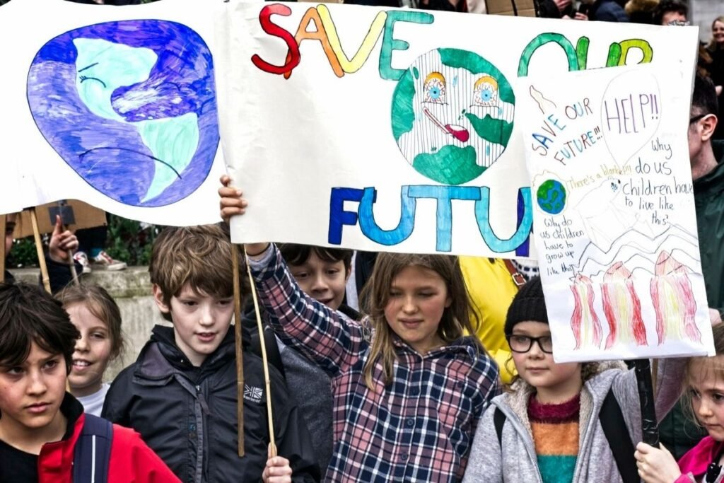 A group of children hold signs with pictures of the Earth and slogans such as "Save Our Future."