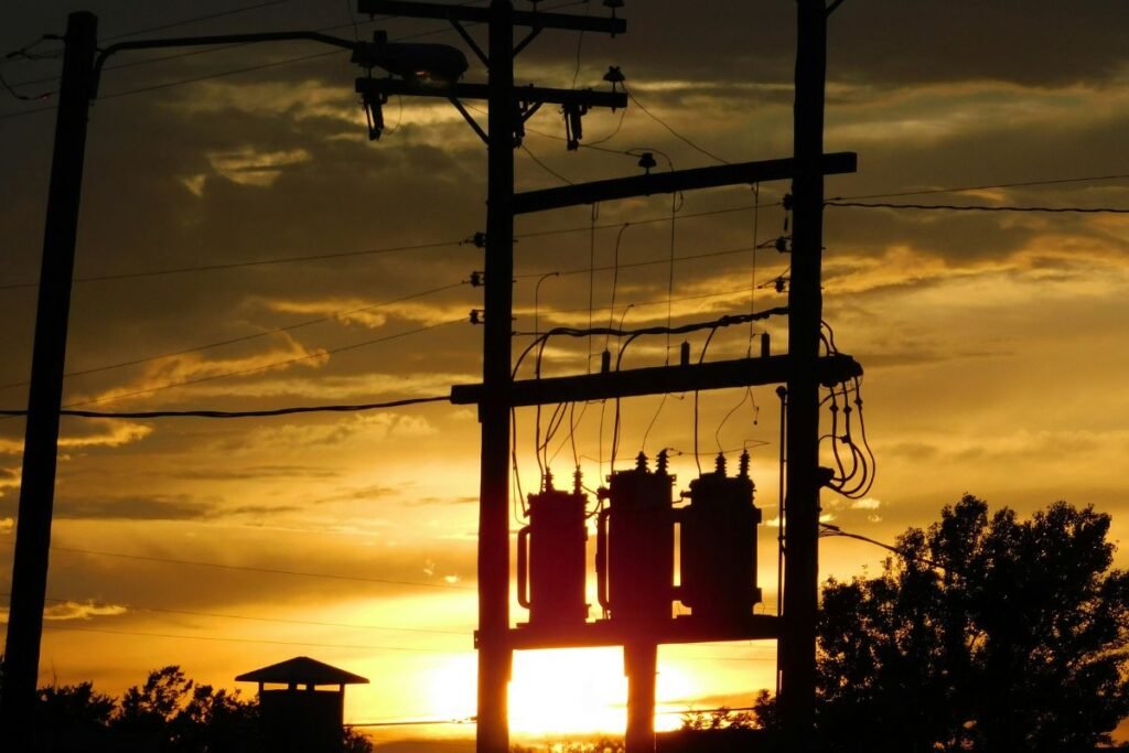 The sun sets behind a lamppost and power lines.