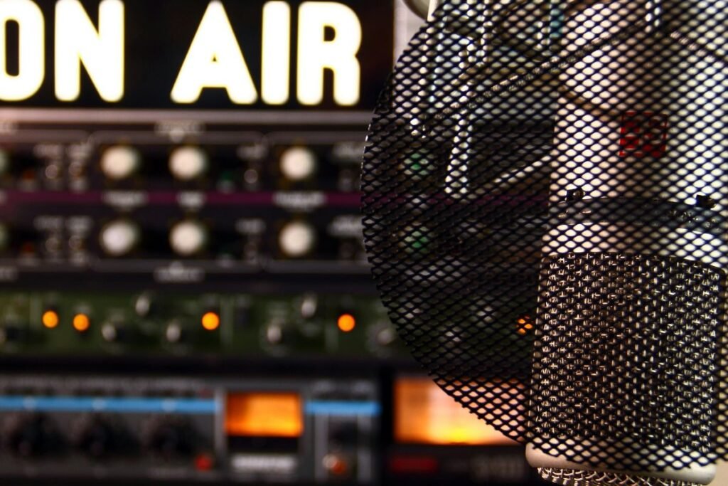 A close-up of radio equipment with an illuminated “On Air” sign in the background.