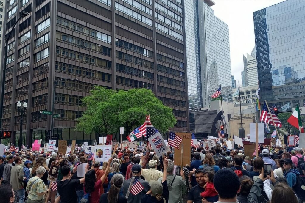A No Kings protest at Washington and Clark in downtown Chicago in June 2025. US flags and signs visible in the background.