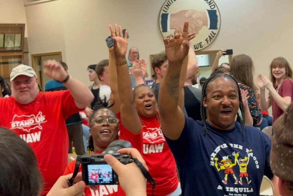 Victory celebration photo after Volkswagen workers in TN vote for union. Three people are wearing red UAW t-shirts.