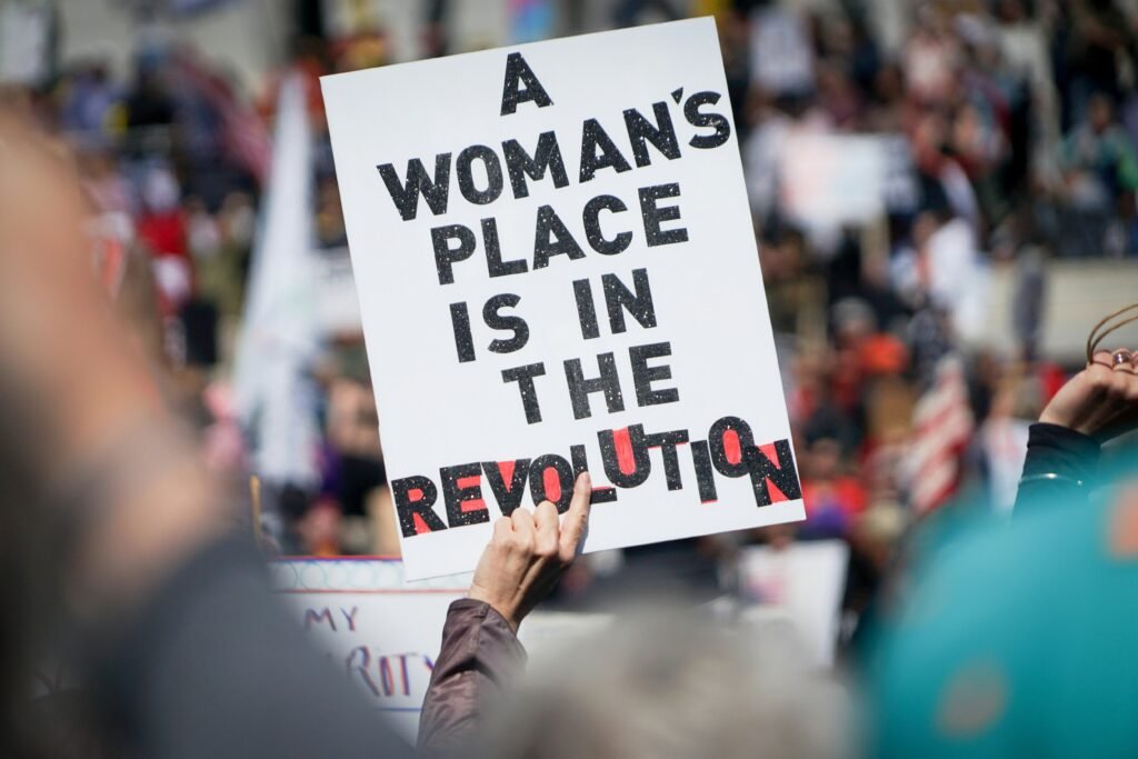 Someone holding a sign during a protest that reads, “A woman’s place is in the revolution.”