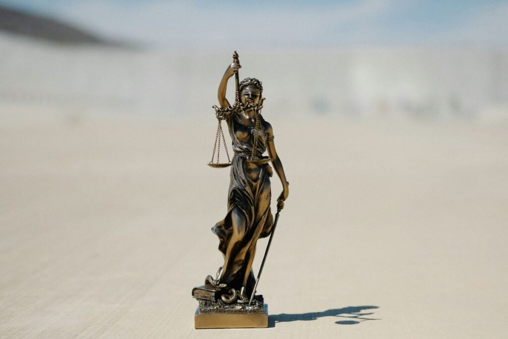 A small statue of Lady Justice with scales on a large concrete patio.