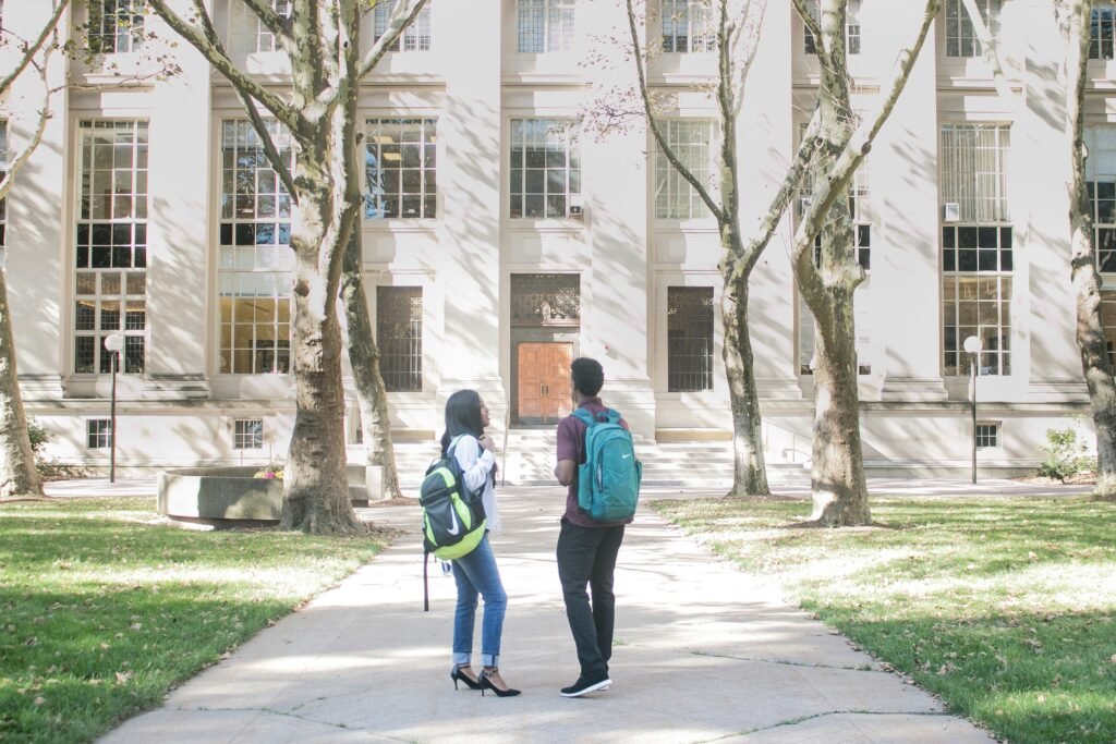 Two people stand outside of the door of a university.