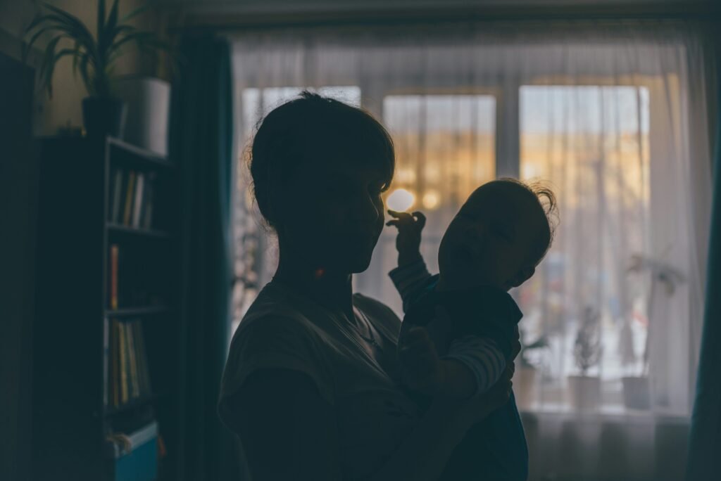 the silhouette of a woman holding a child in front of a window.