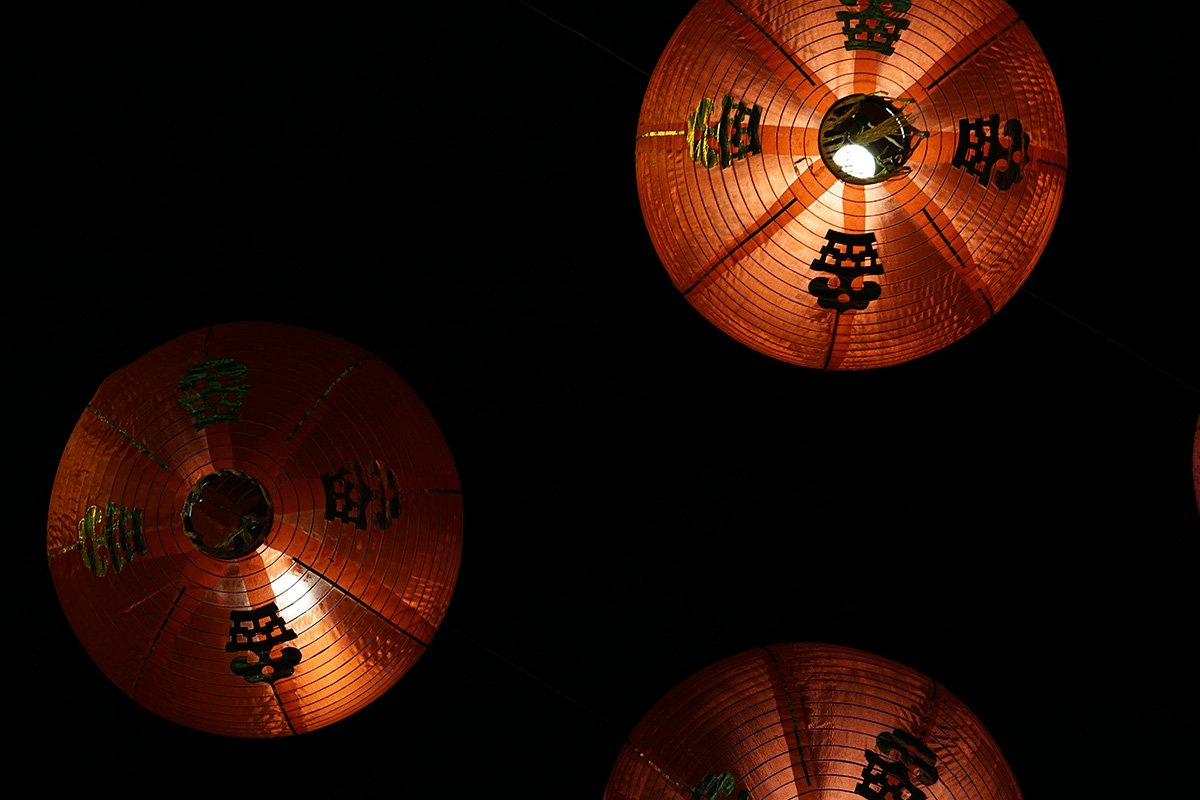 Looking up at circular paper lanterns in a dark room