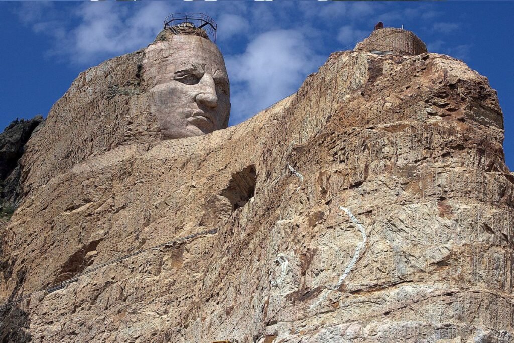 The face of Crazy Horse is carved into the Black Hills of South Dakota. Below the enormous face is a long, outstretched arm.