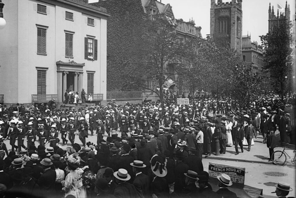In a black-and-white photo hundreds, including US Steel strikers, march in formation on Labor Day in New York City in 1908.