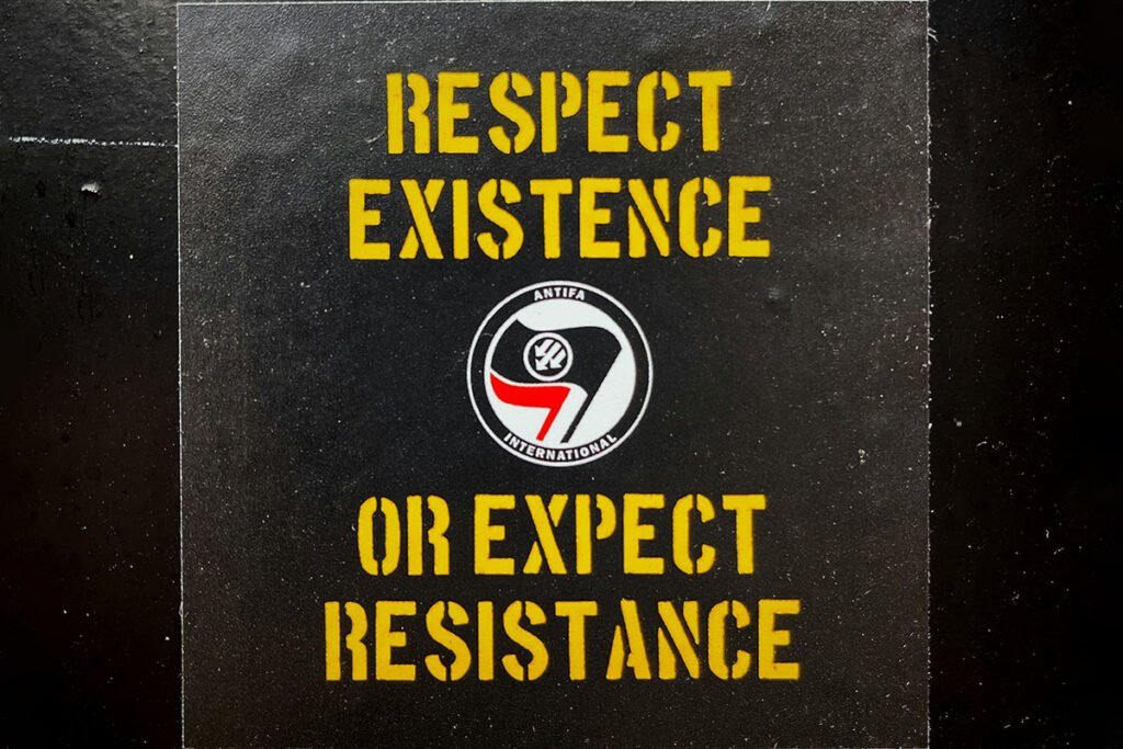 A poster reading “Respect Existence or Expect Resistance” with an antifa emblem in the center.
