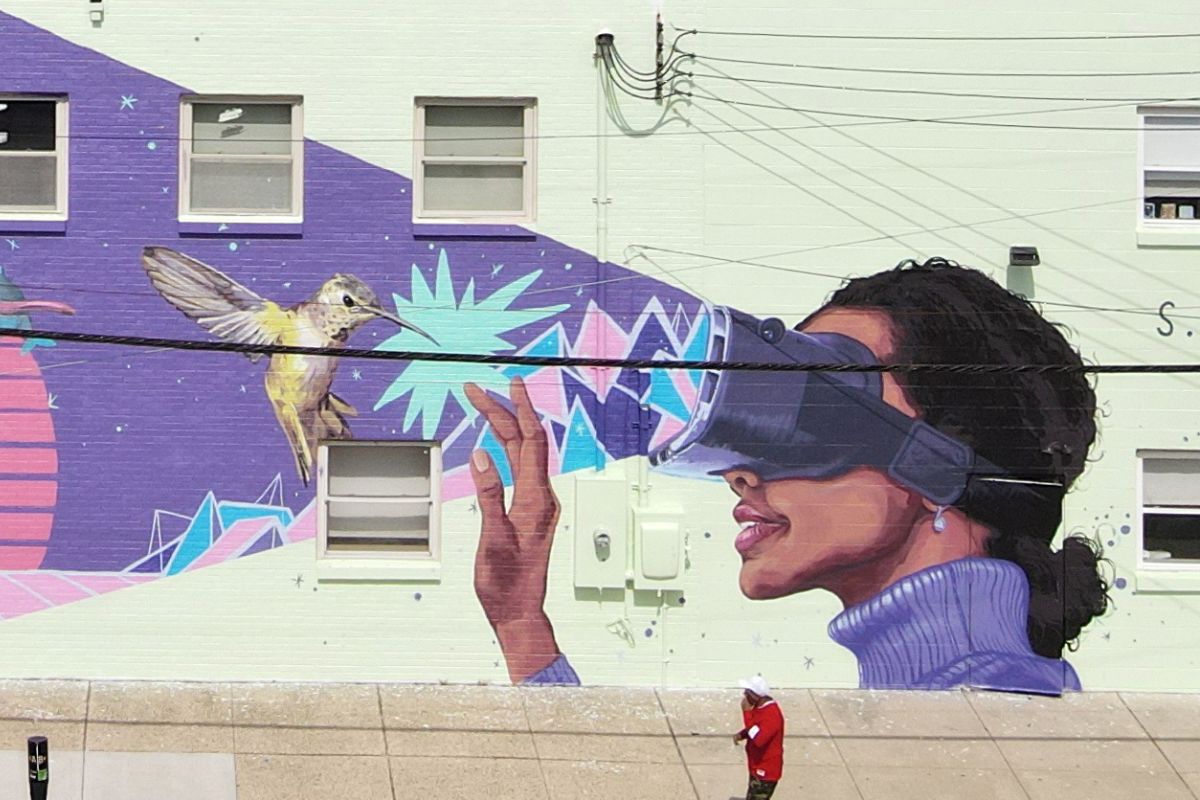 Mural of a girl wearing a VR headset projecting colorful shapes toward a hummingbird, with the words “S.T.E.A.M. DREAMS” on a light green wall.