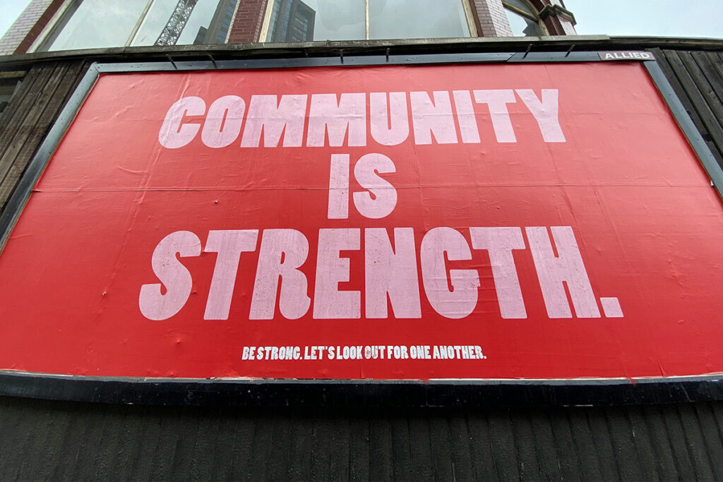 A sign that reads, “Community is Strength. Be Strong. Let’s look out for one another.”