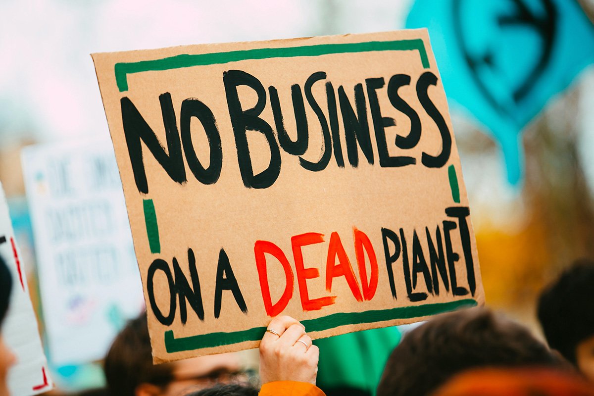 A protest sign reading, “No Business on a dead planet”, emphasizing how the wellbeing of our planet is more important than profit.