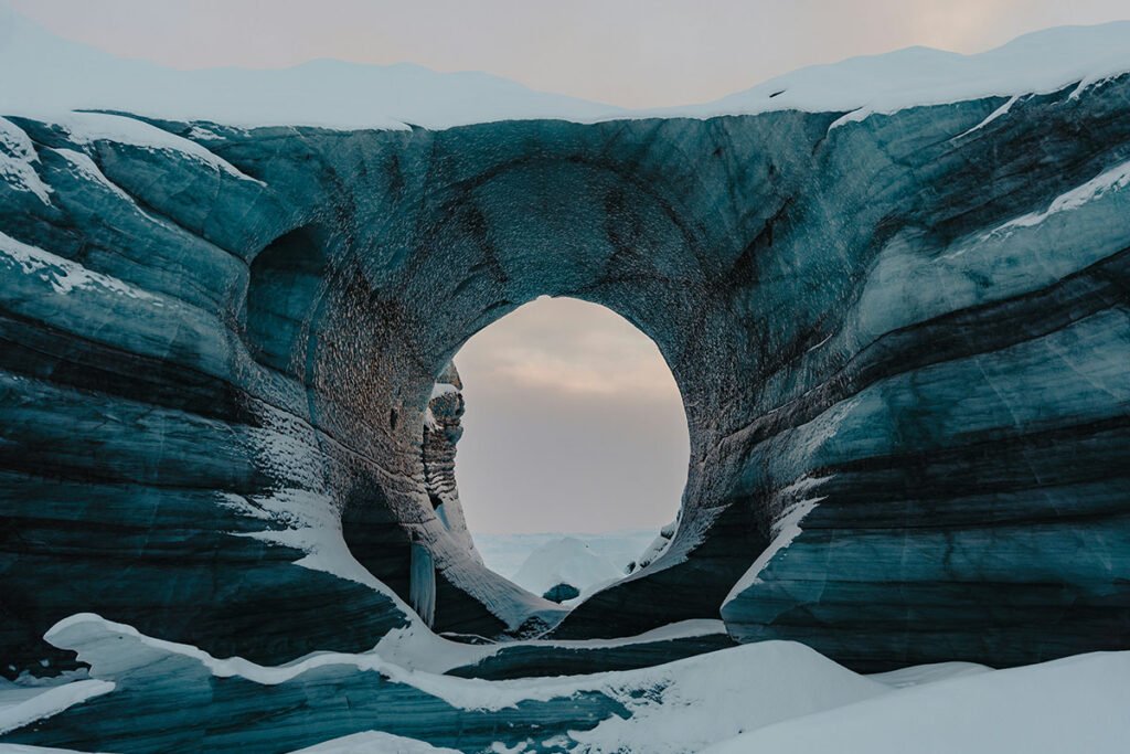 A portal-like hole carved out in a glacier, representing opportunity and opened doors.