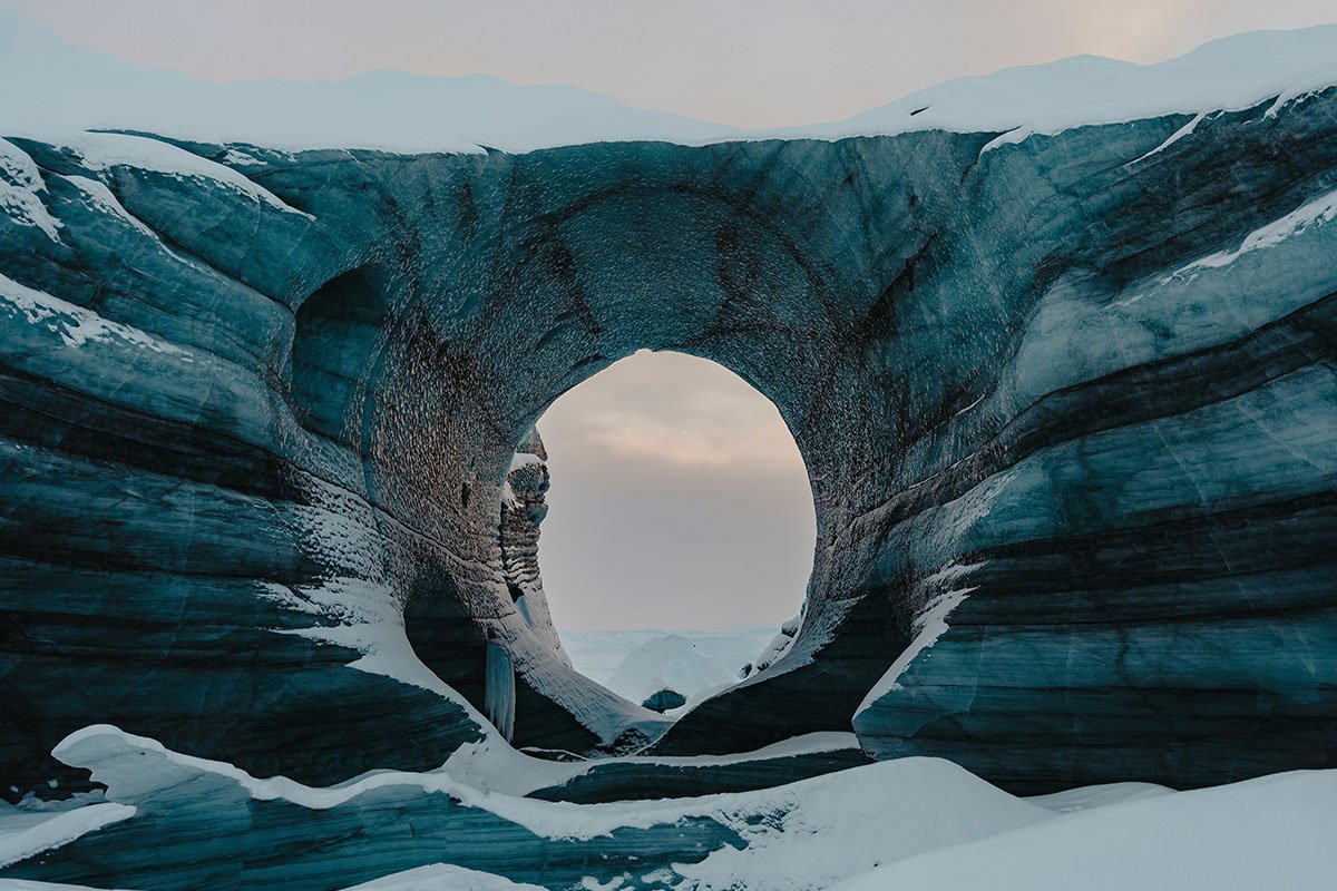 A portal-like hole carved out in a glacier, representing opportunity and opened doors.