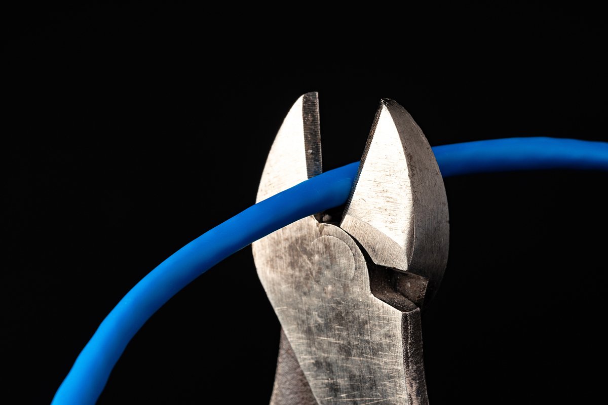 A pair of pliers cutting a blue wire, symbolizing cutting off blue-state funding sources for Trump.