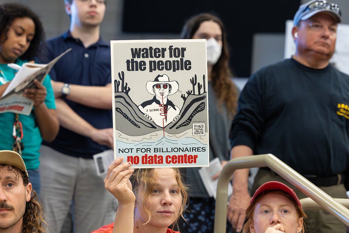 A woman holding up a protest sign reading, “water for the people. Not for billionaires. No data center.”