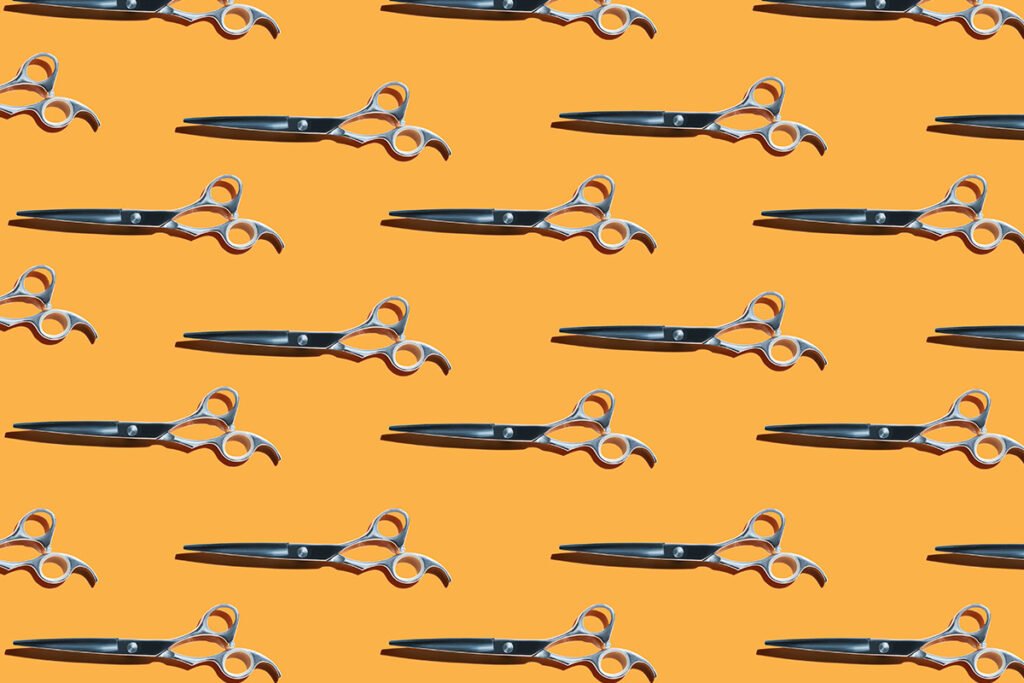 Rows of scissors lined up against a yellow background, representing federal funding cuts.