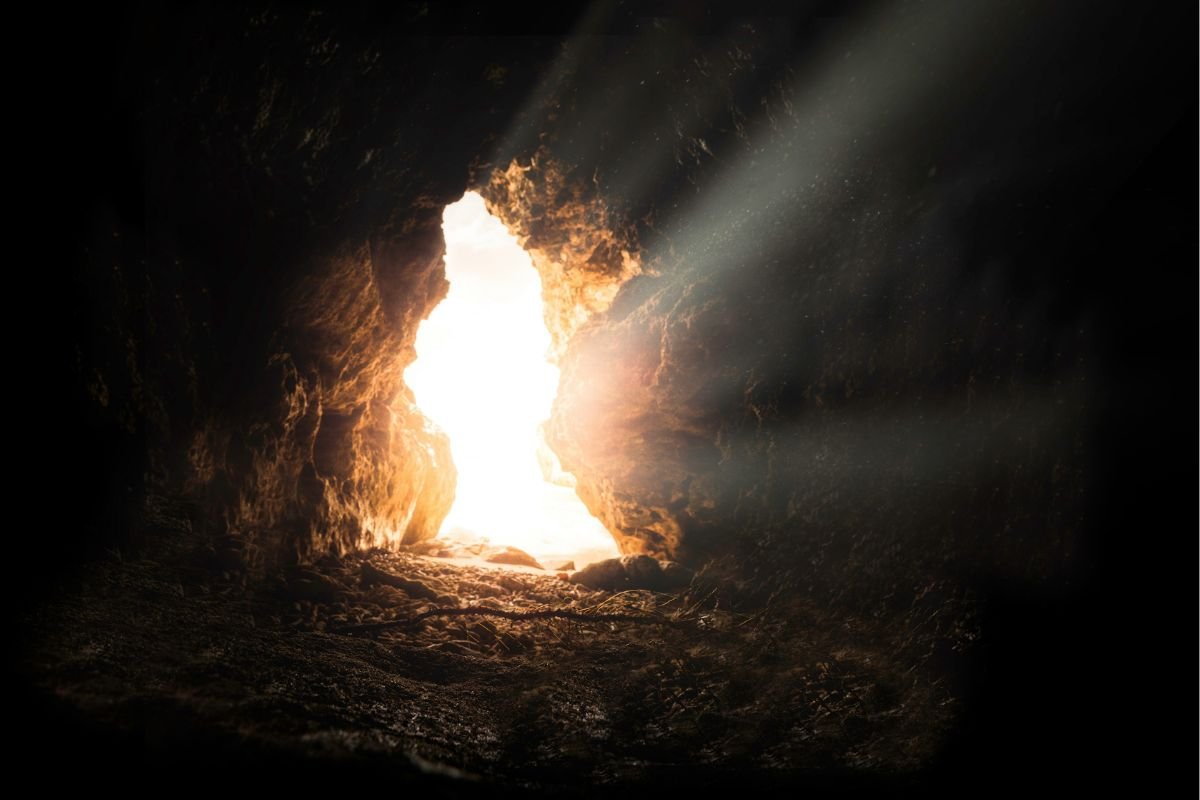 Sun rays shine through an opening in dark rock, emphasizing possibility during difficult times.