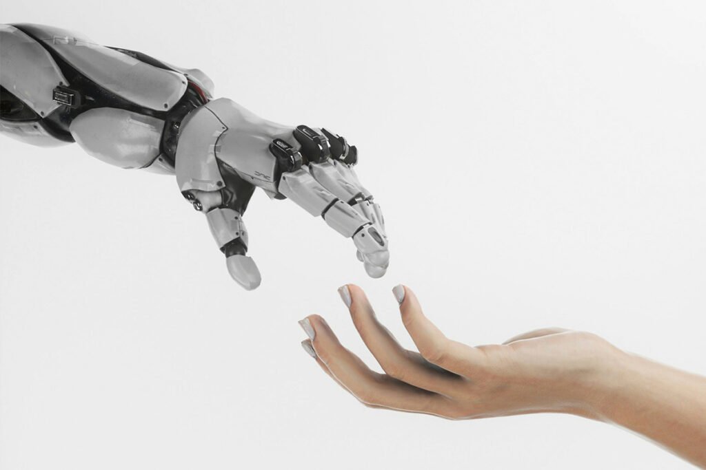 A robot hand reaching slightly downward to touch a human hand, representing the human influence on AI and vise versa.