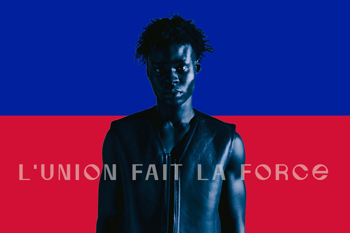 A dark skin Black man washed in blue light, looking directly at the camera in front of a blue and red background, mirroring the Haitian flag. The words, “L’union fait la force” are superimposed on the image.