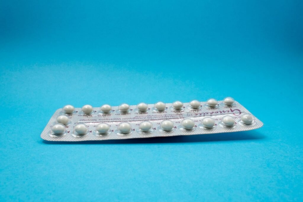 A metallic packet of small white pills rests on a blue background.