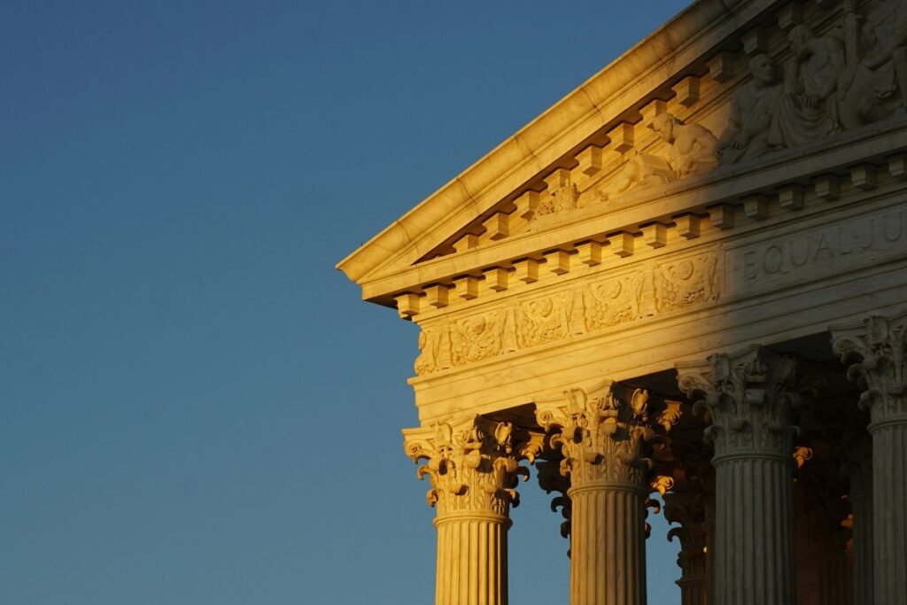 Detail of a corner of the US Supreme Court against a blue sky.