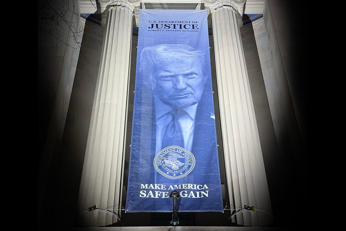 Banner showing U.S. President Donald Trump with the slogan “Make America Safe Again,” installed between the columns of the Robert F. Kennedy Department of Justice Building, Washington, D.C., February 19, 2026.
