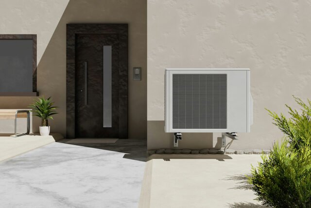 A heat pump installed on the exterior of a modern-style, stucco home.