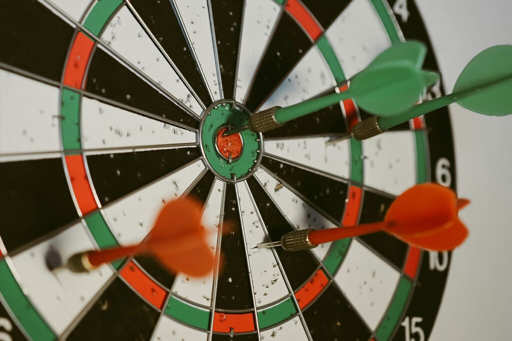 A close up of a target with several planted darts, including one bullseye shot.