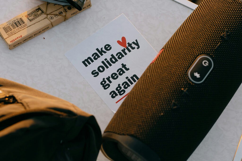 A card tucked under a portable speaker that reads, “make solidarity great again”