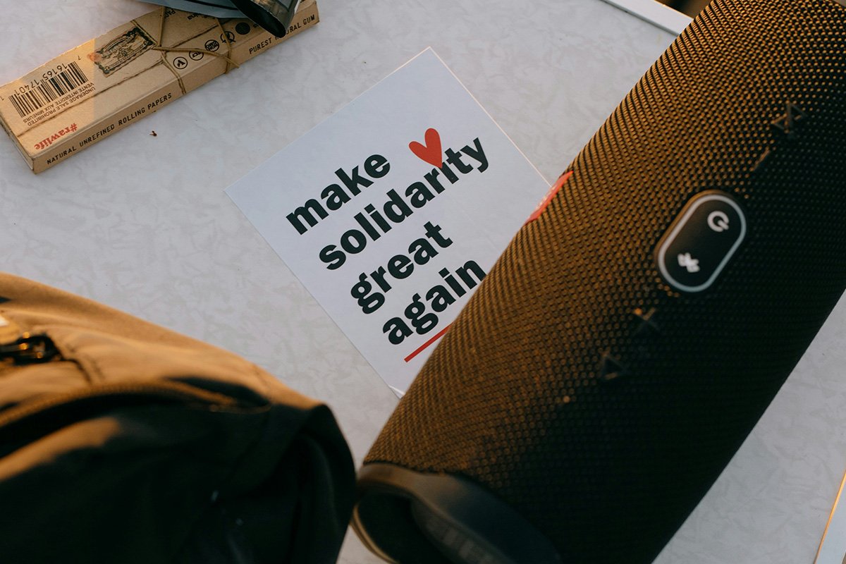 A card tucked under a portable speaker that reads, “make solidarity great again”