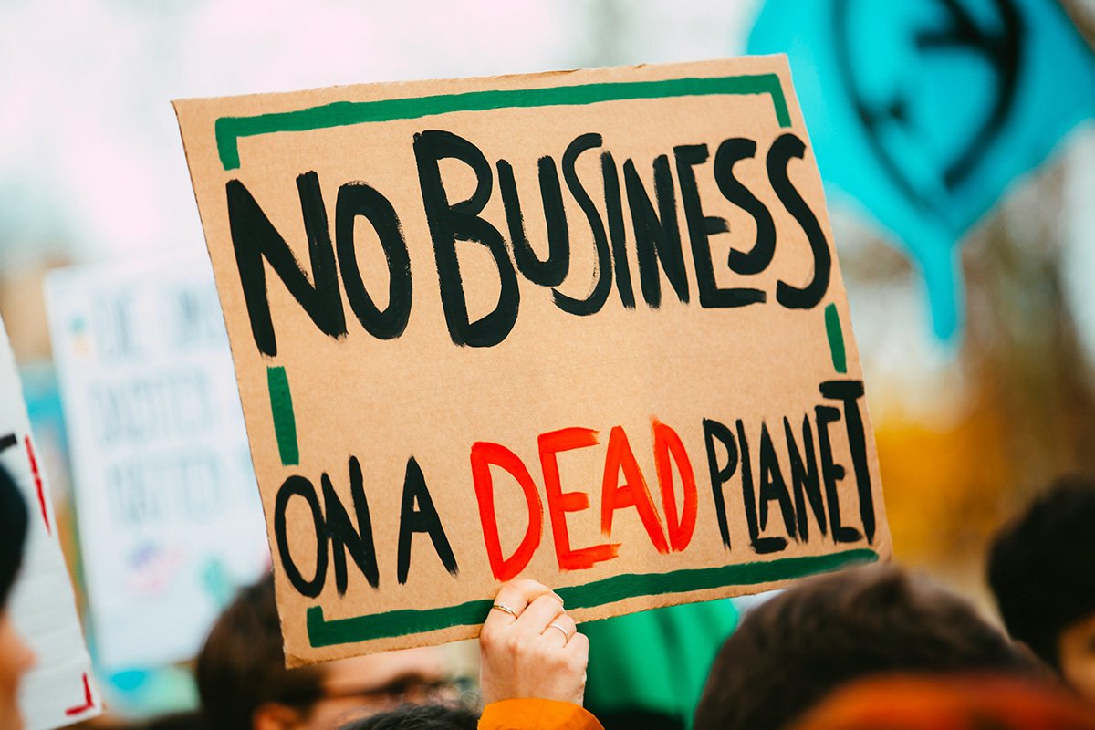 A person holding up a sign that reads, “No Business on a dead planet”, underscoring that if climate change isn’t taken seriously, nothing else can exist.