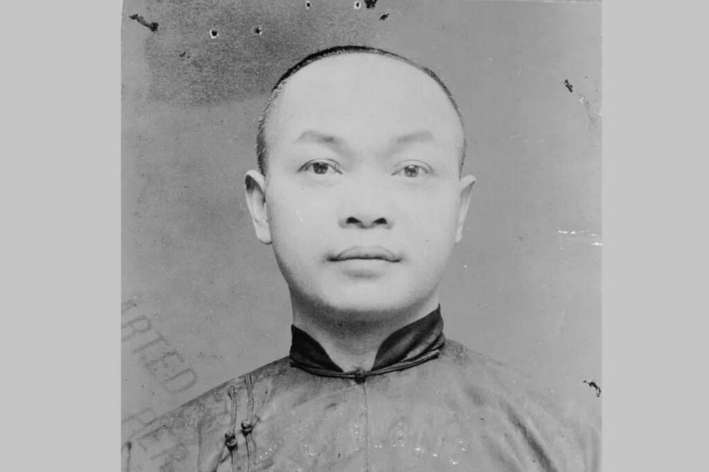 Historic black-and-white portrait of a young Chinese man wearing a traditional high-collared tunic, photographed from the chest up against a plain background.
