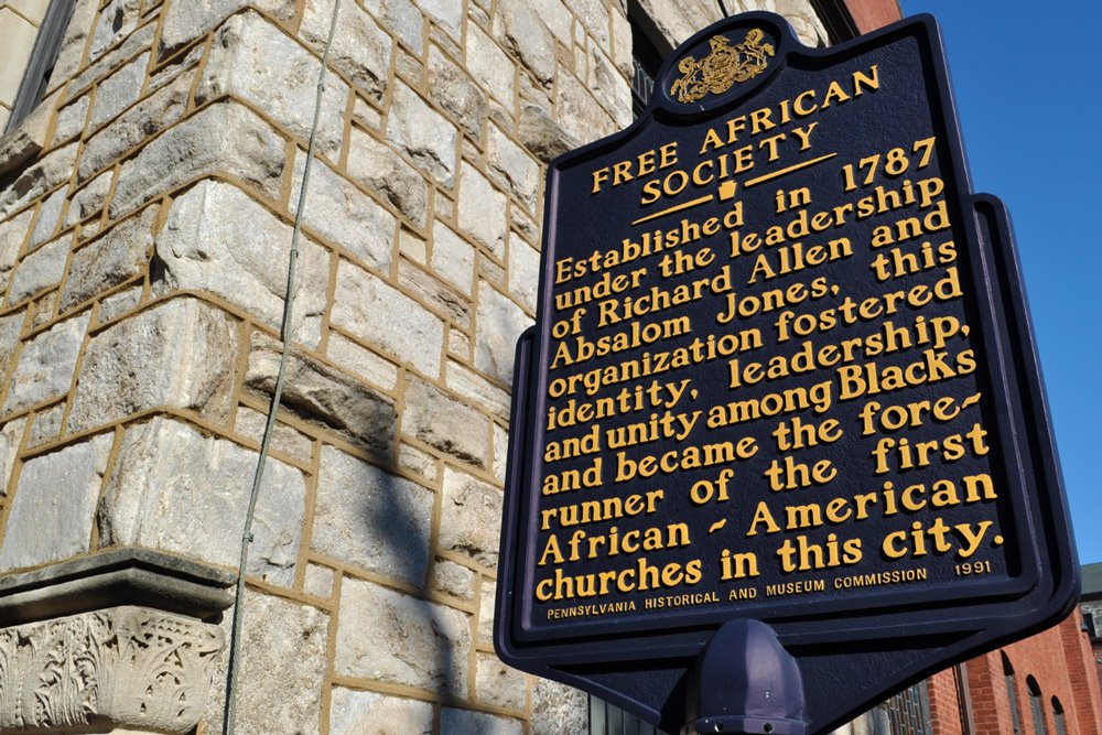 Pennsylvania Historical and Museum Commission marker for the Free African Society, established in 1787 under the leadership of Richard Allen and Absalom Jones, mounted outside a stone church building in Philadelphia.
