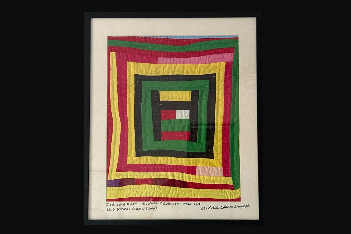 A quilted piece of red, yellow, green, black, and pink strips. “Pig in a Pen”