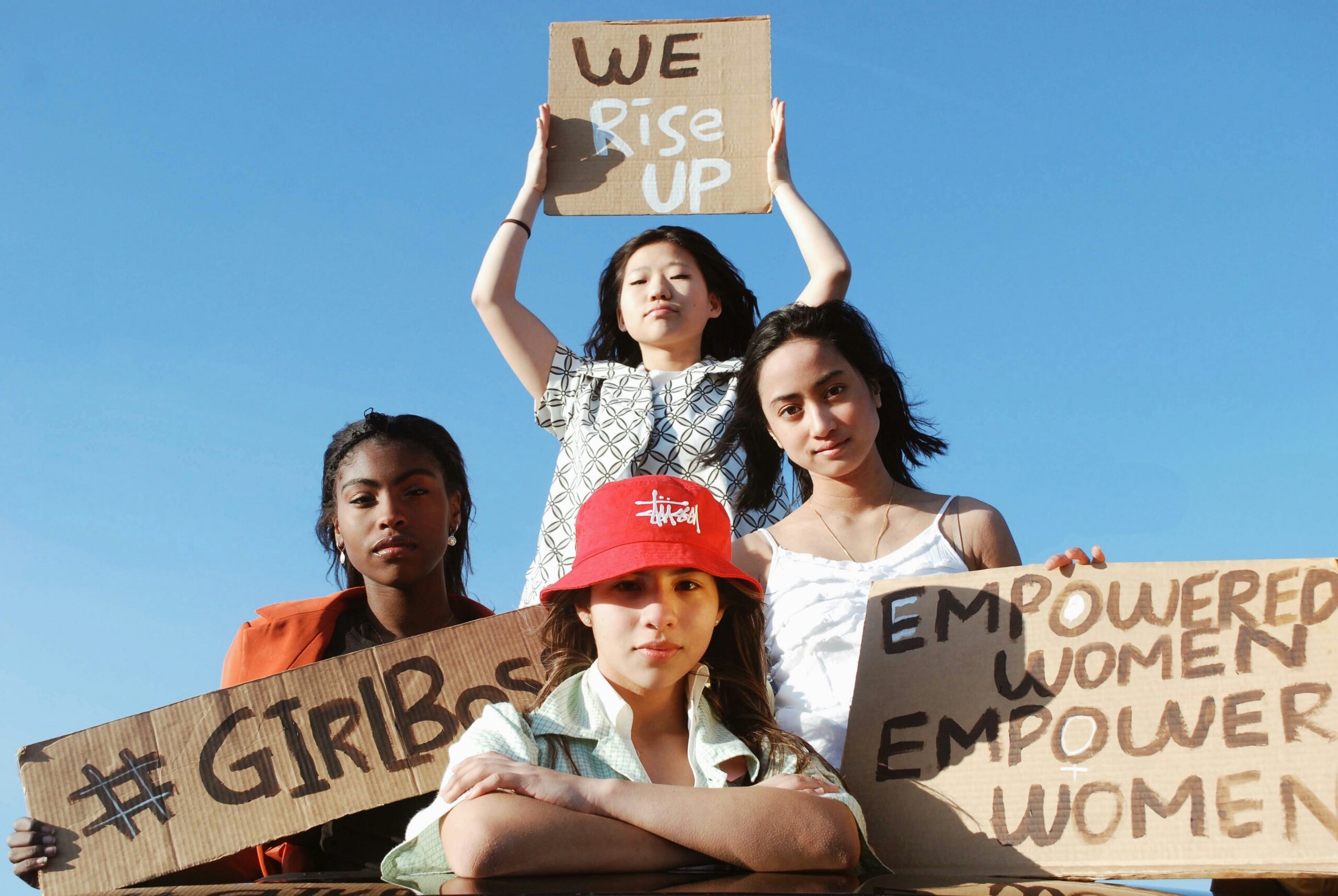 Three women holding signs about empowering other women.