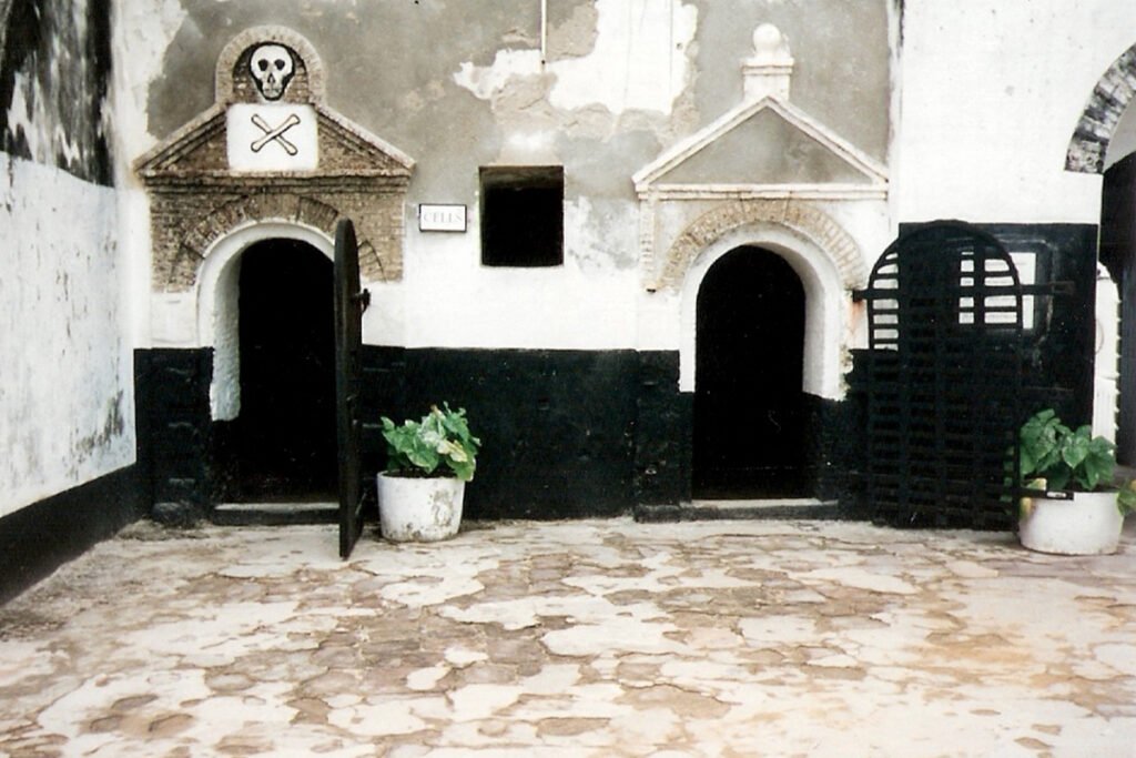 The exterior of a barred room with a skull and crossbones over the door. Elmina fortress, Elmina, Ghana.