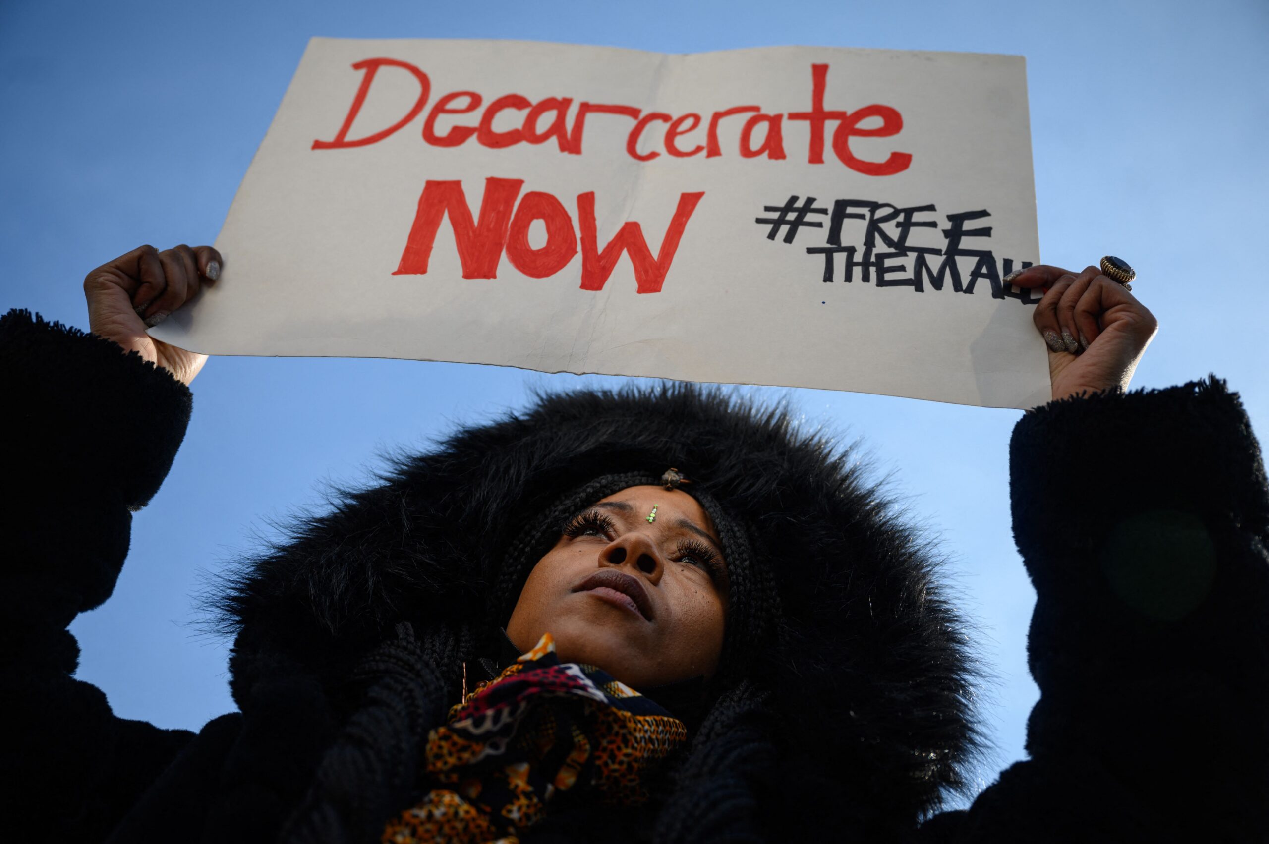 Dr. Victoria A Phillips, co-chair of the NYC Department of Corrections Young Adult Task Force, holds a placard reading "Decarcerate Now" during a rally in solidarity with inmates on hunger strike, at the entrance to the Rikers Island jail complex in Queens, New York on January 13, 2022. (Photo by Ed JONES / AFP) (Photo by ED JONES/AFP via Getty Images)