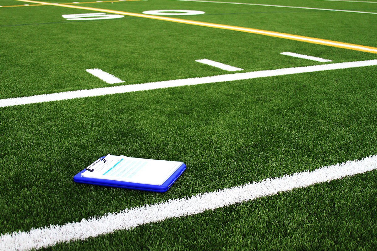 A blue playbook on a green football field in a youth scrimmage.