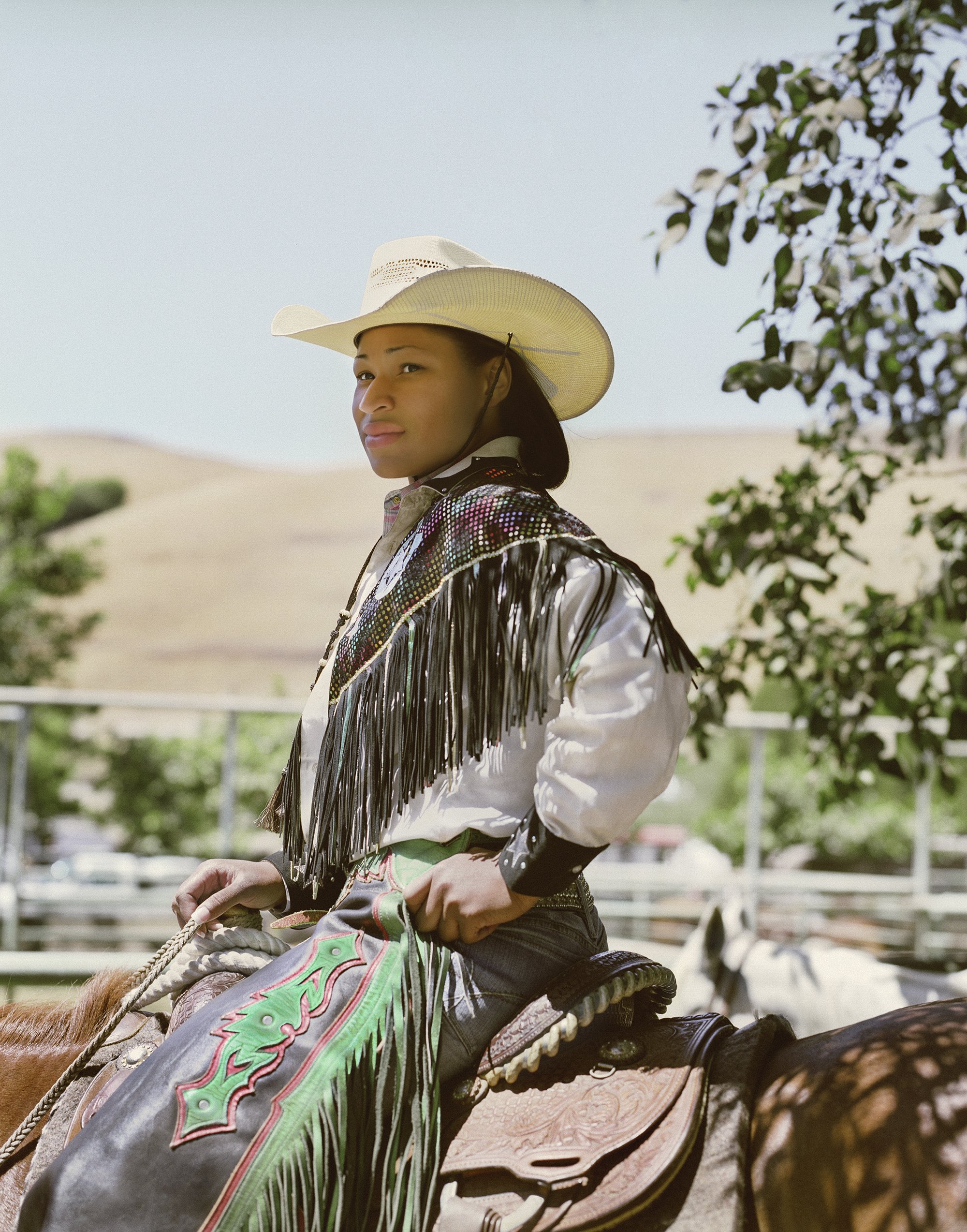 Cowgirl Denesha Henderson at the BPIR in Oakland, 2008. “The outfit that I have on is what I wore when carrying the African American flag in the very beginning of the rodeo,” Denesha Henderson explains about this image from 2008. “It’s tradition to wear the chaps and the decorative shirt. That’s how we pay tribute to both the American flag and African American flag.” Denesha has been competing at the BPIR for more than twenty-four years. “The rodeo and horses are definitely the one thing that has always remained constant in my life,” she says. Photograph by Gabriela Hasbun.