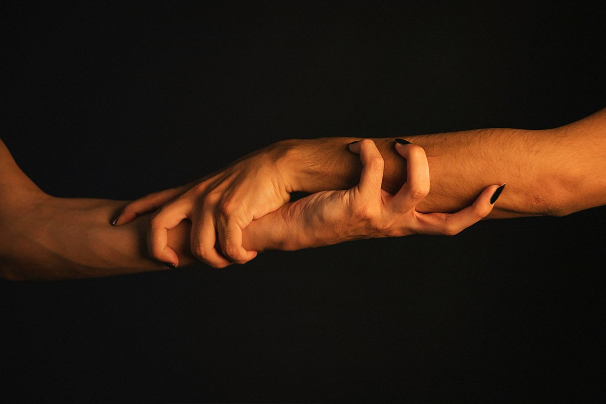Two arms grasping at each other by grabbing each others' wrists.