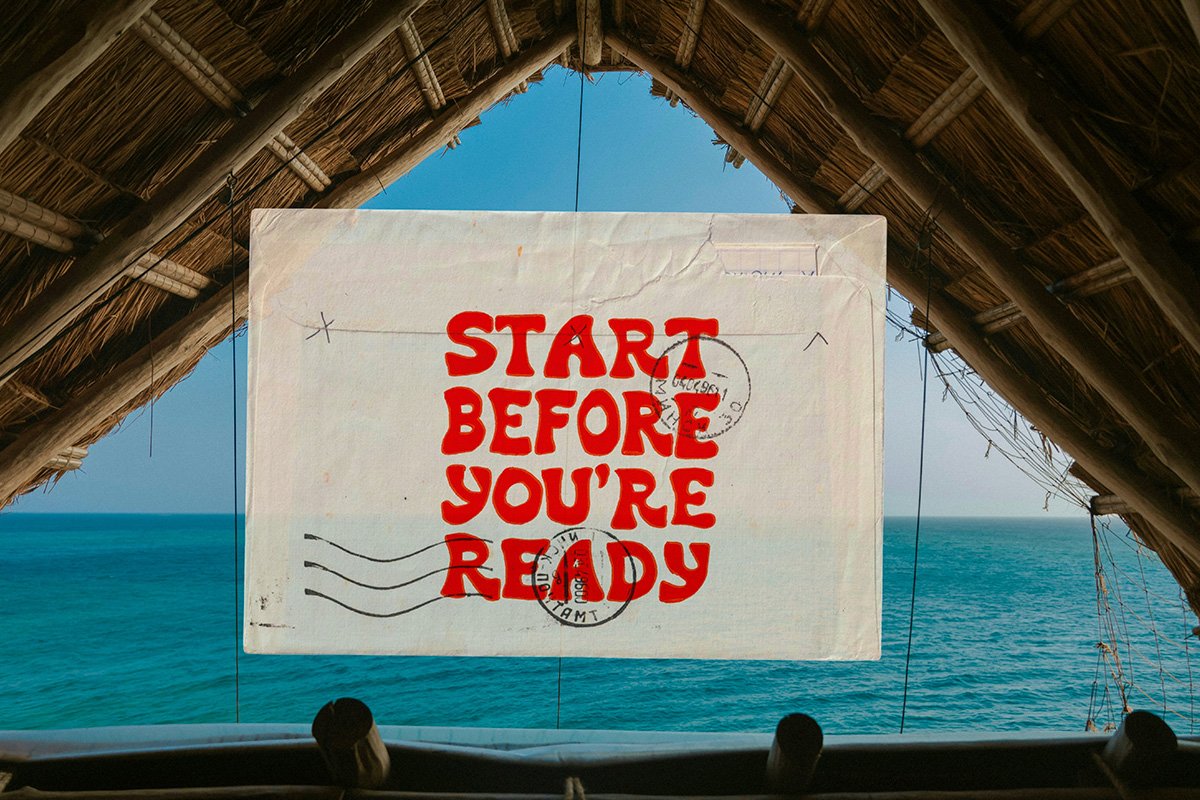 A composition of a postcard with the words “start before you’re ready” superimposed over an image of a hut overlooking the ocean.